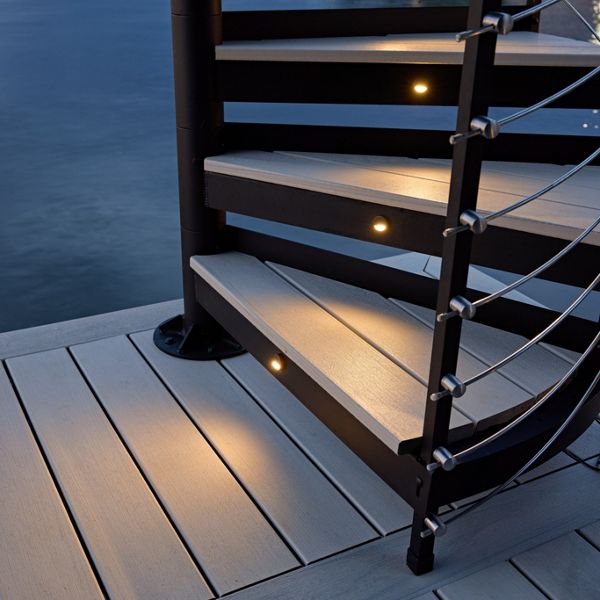 A close up view of Trex Spiral Stairs with Trex lighting illuminating the stairs up.